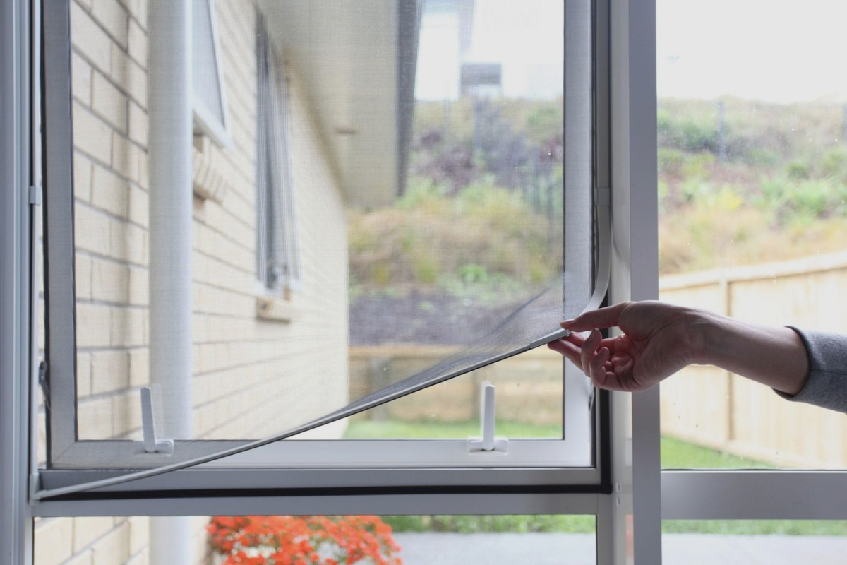 A person removing a mosquito net to clean it