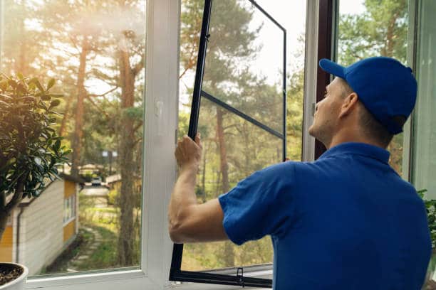 Homem a instalar uma rede de proteção contra insectos na janela