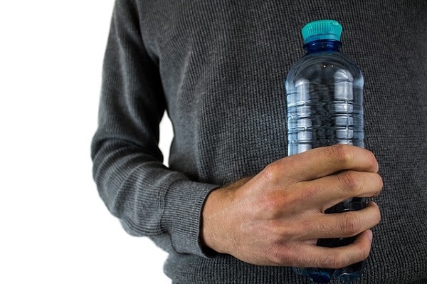 homem segurando uma garrafa de plástico na sua mão