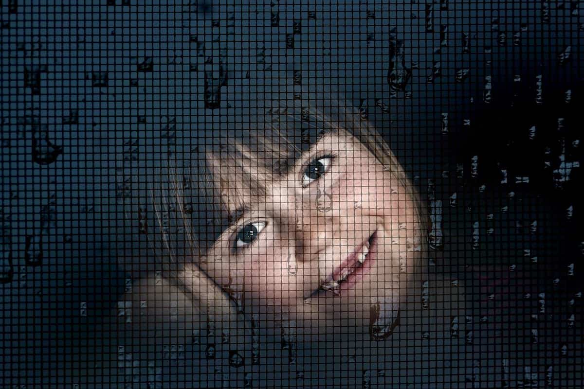 girl looking at mosquito net on aluminum window