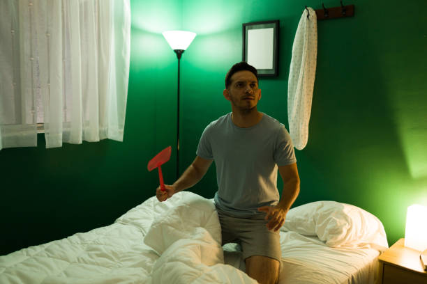 hombre intentando matar mosquitos en una habitación