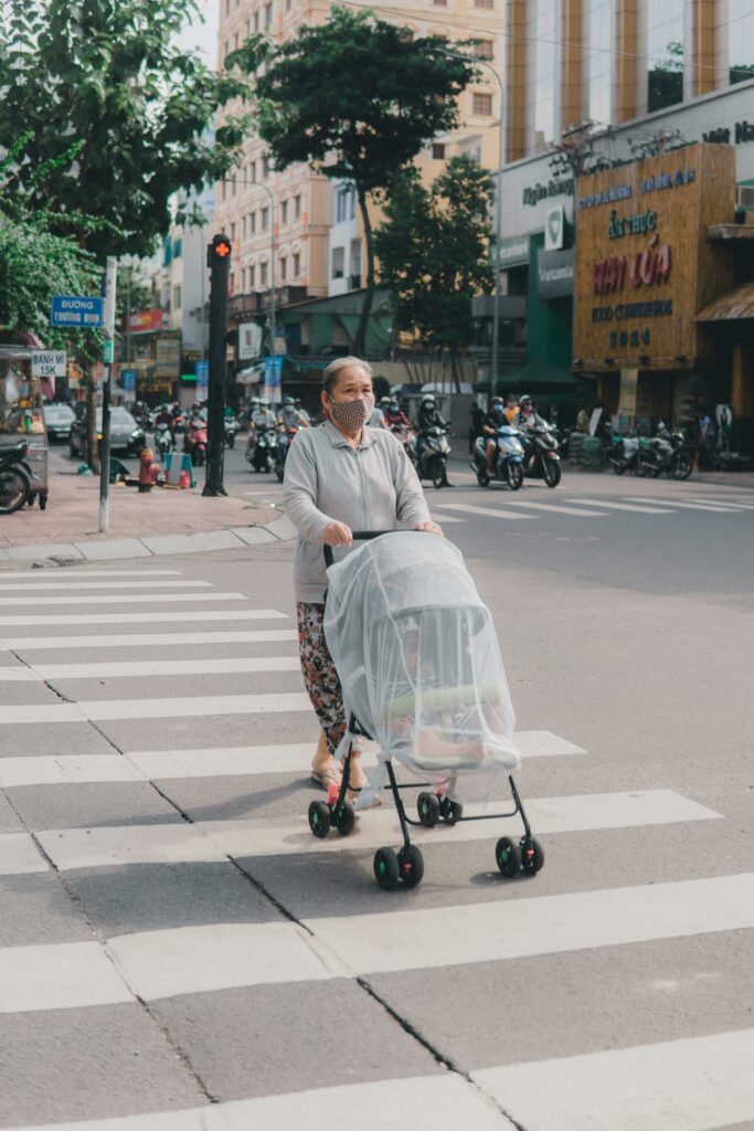 femme âgée promenant son bébé dans une poussette avec moustiquaire