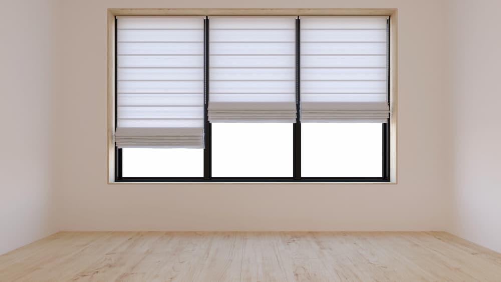 Estores plegables blancos en ventana de tres hojas con caja de persiana